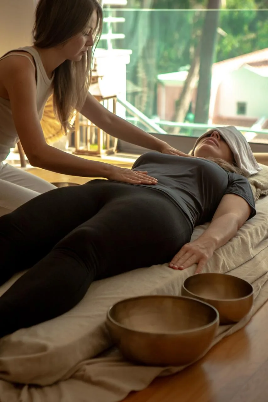 Practitioner offering a quiet sound ritual beside singing bowls